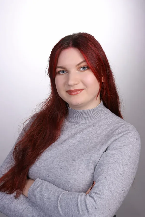 Palina, Porträt mit langen roten Haaren und verschränkten Armen.